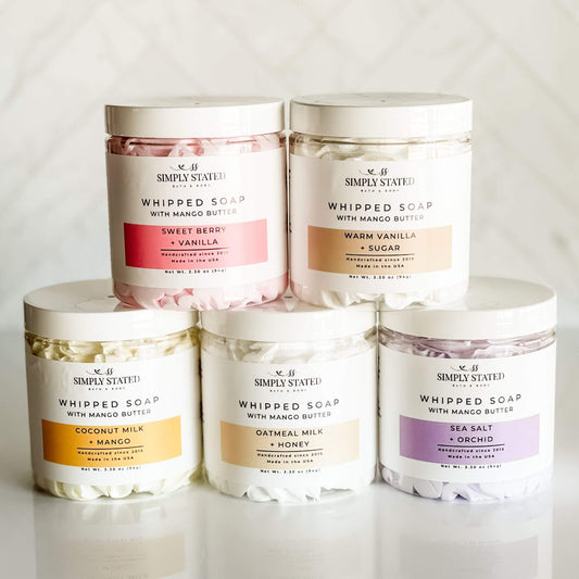 Collection of Signature Line Whipped Soaps in various scents, including Coconut Milk + Mango, Sweet Berry + Vanilla, Warm Vanilla + Sugar, Oatmeal Milk + Honey, and Sea Salt + Orchid, displayed in 8oz jars with whipped textures.